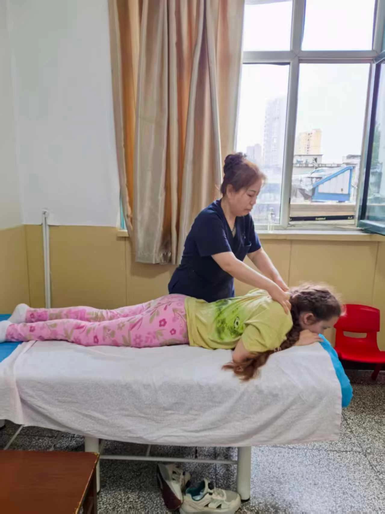 Специалист по туйна Ли Хуэйли продолжает сеанс массажа с ребёнком