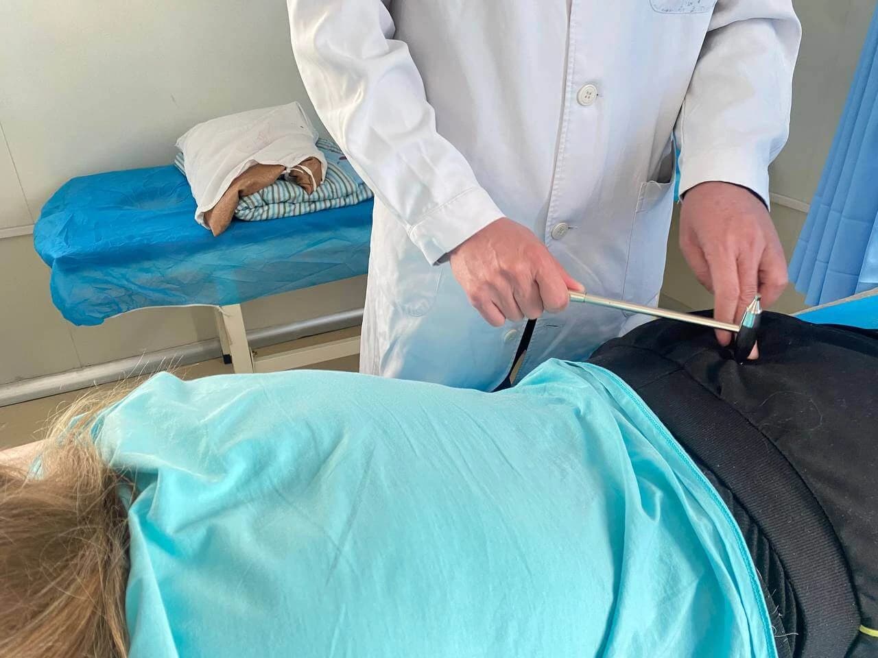 Врач выполняет процедуру меридиональной стимуляции в палате центра реабилитации