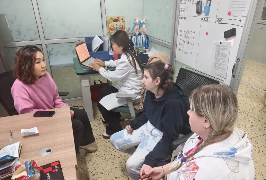 Кабинет специалиста: сотрудница в белом халате за компьютером, рядом сидят мамы с детьми