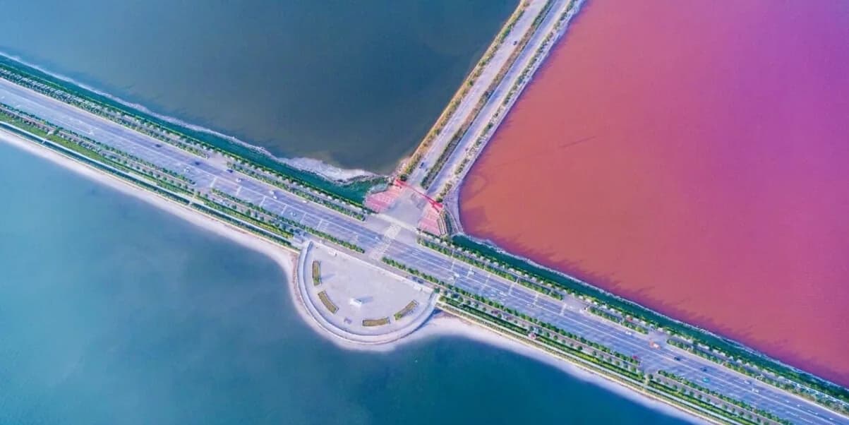 Аэрофото солёного озера Юньчэна: розовая и голубая вода по разные стороны дороги через дамбу